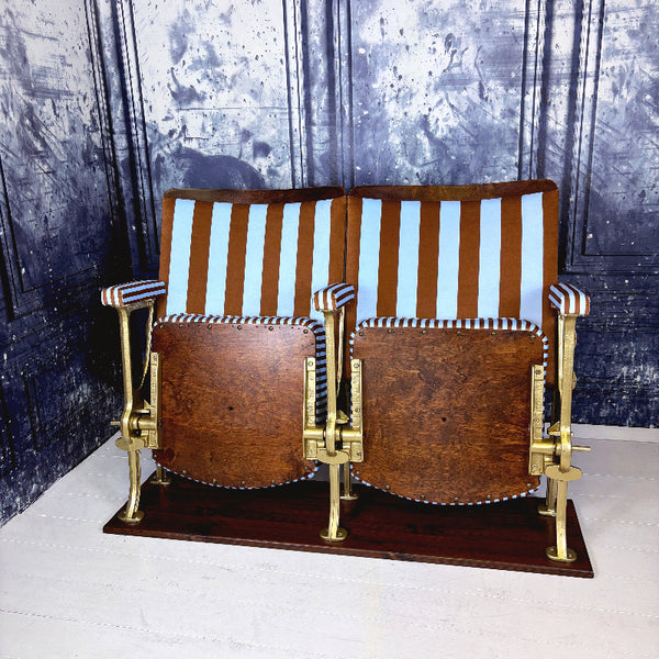 Striped vintage cinema seats with brown and blue velvet from colours of arley on a white floor against a textured wall.