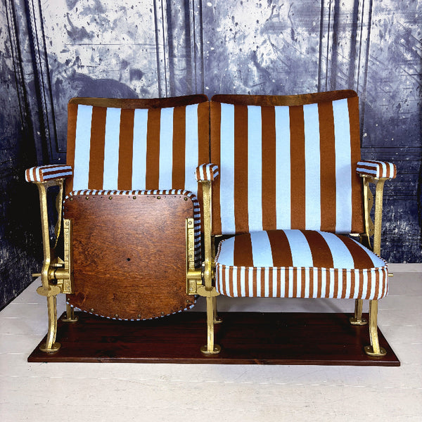 Striped vintage cinema seats with brown and blue velvet from colours of arley on a white floor against a textured wall.