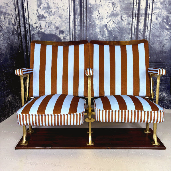 Striped vintage cinema seats with brown and blue velvet from colours of arley on a white floor against a textured wall.