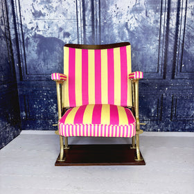 Vintage cinema seat with pink and yellow striped velvet from colours of arley, against a textured blue wall.