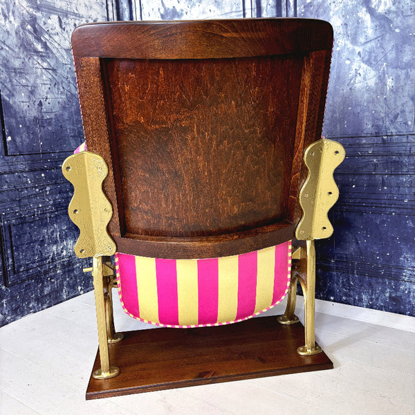 Vintage cinema seat with pink and yellow striped velvet from colours of arley, against a textured blue wall.