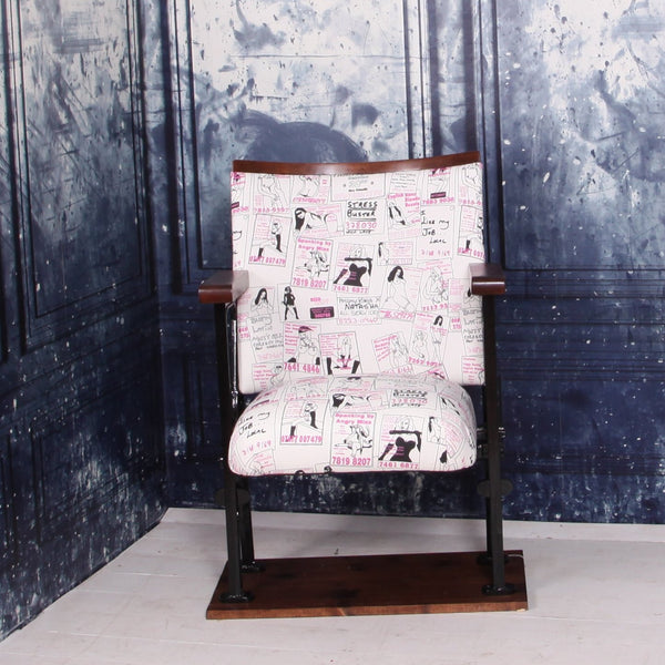 a vintage cinema seat upholstered in a call girl fabric with black gloss legs against a blue marbled wall