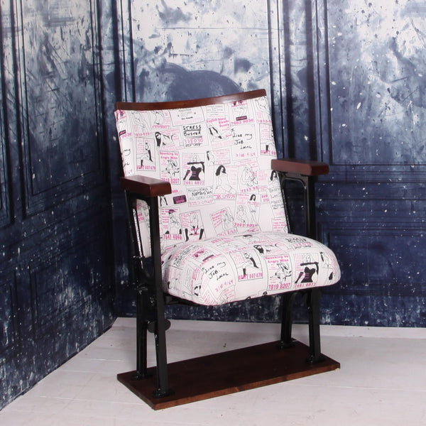 a vintage cinema seat upholstered in a call girl fabric with black gloss legs against a blue marbled wall