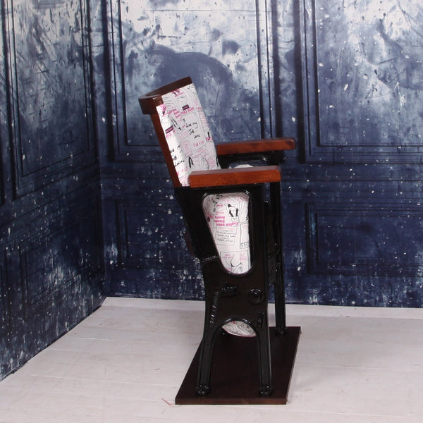 Side view of a vintage cinema seat upholstered in a call girl fabric with black gloss legs against a blue marbled wall