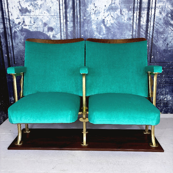Set of two refurbished vintage cinema seats upholstered in green velvet.  The seats are against a blue marbled wall