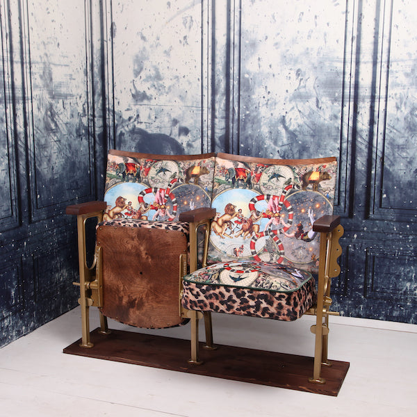 a set of two vintage cinema seat against a marbled blue wallpaper. Cinema seats are upholstered in cirque du monde velvet with leopard print border