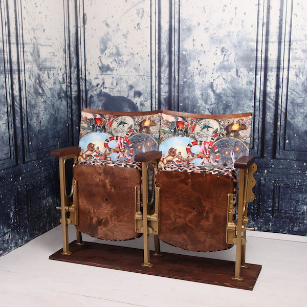 a set of two vintage cinema seat against a marbled blue wallpaper. Cinema seats are upholstered in cirque du monde velvet with leopard print border