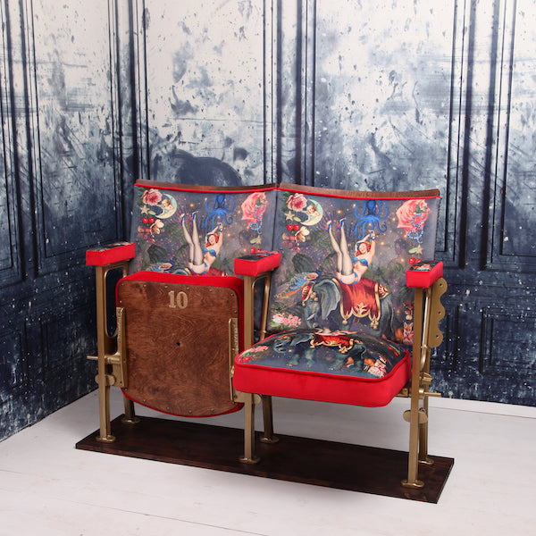 a set of two vintage cinema seat against a marbled blue wallpaper. Cinema seats are upholstered in Fifi velvet with red velvet piping and border
