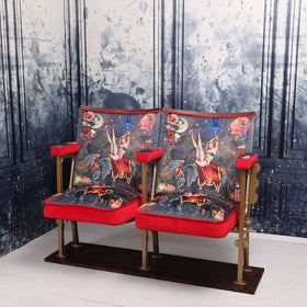 a set of two vintage cinema seat against a marbled blue wallpaper. Cinema seats are upholstered in Fifi velvet with red velvet piping and border
