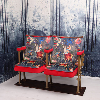 a set of two vintage cinema seat against a marbled blue wallpaper. Cinema seats are upholstered in Fifi velvet with red velvet piping and border