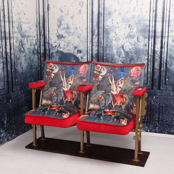 a set of two vintage cinema seat against a marbled blue wallpaper. Cinema seats are upholstered in Fifi velvet with red velvet piping and border
