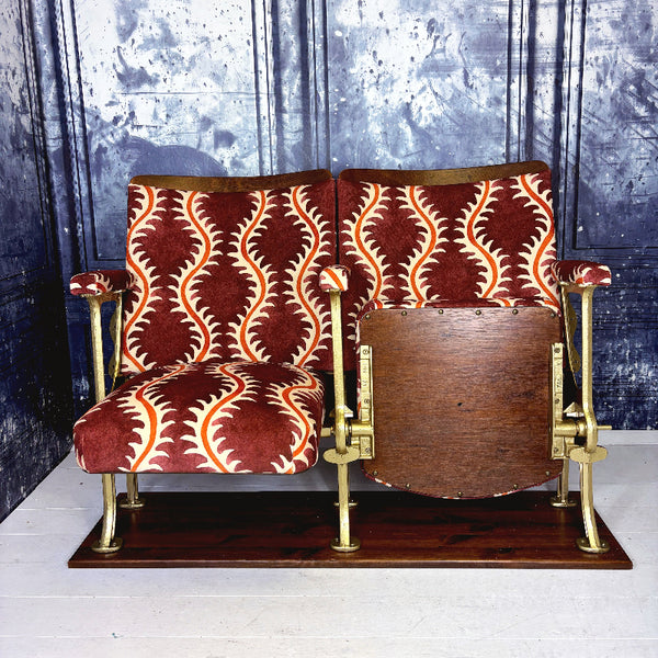 Vintage cinema seat with redcurrant and orange patterned upholstery on a wooden base.