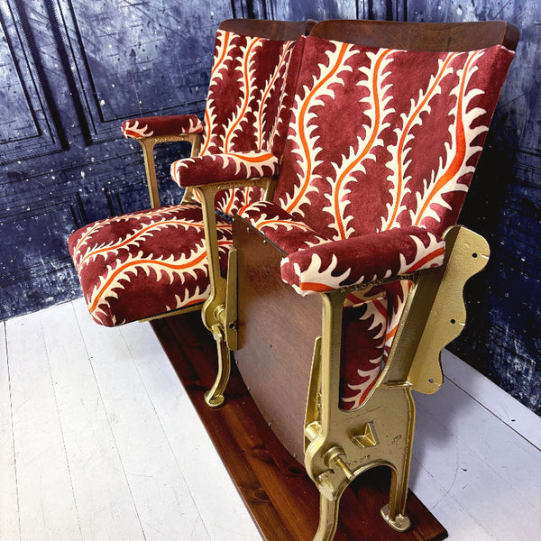 Vintage cinema seat with redcurrant and orange patterned upholstery on a wooden base.