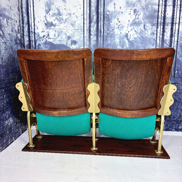 Pair of vintage theater seats with wooden backrests and teal seats on a white background