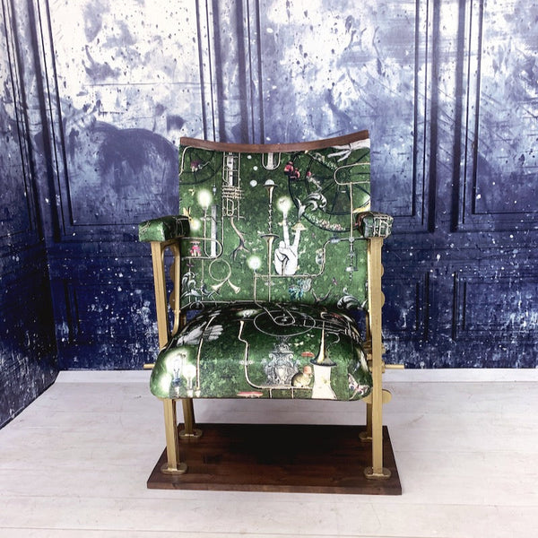 A single vintage cinema seat upholstered in a green velvet with mice and brass instruments on it.  The seat is open