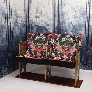 a set of two vintage cinema seat against a marbled blue wallpaper. Cinema seats are upholstered in Paradise Lost velvet with orange velvet piping and black velvet border