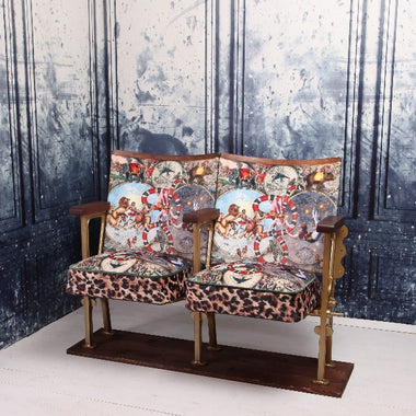 a set of two vintage cinema seat against a marbled blue wallpaper.  Cinema seats are upholstered in cirque du monde velvet with leopard print border